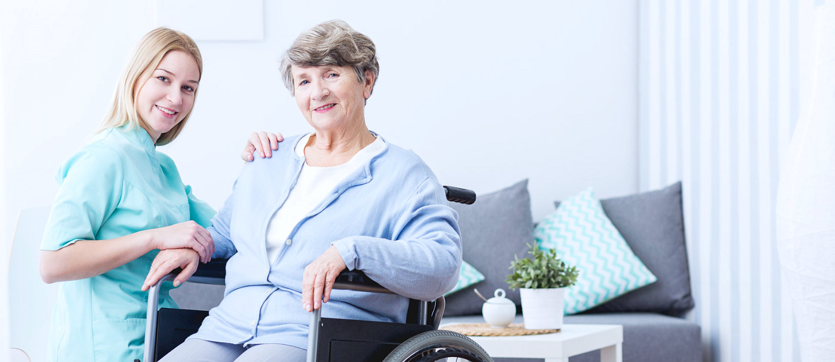 Caregiver with elderly woman in wheelchair smiling