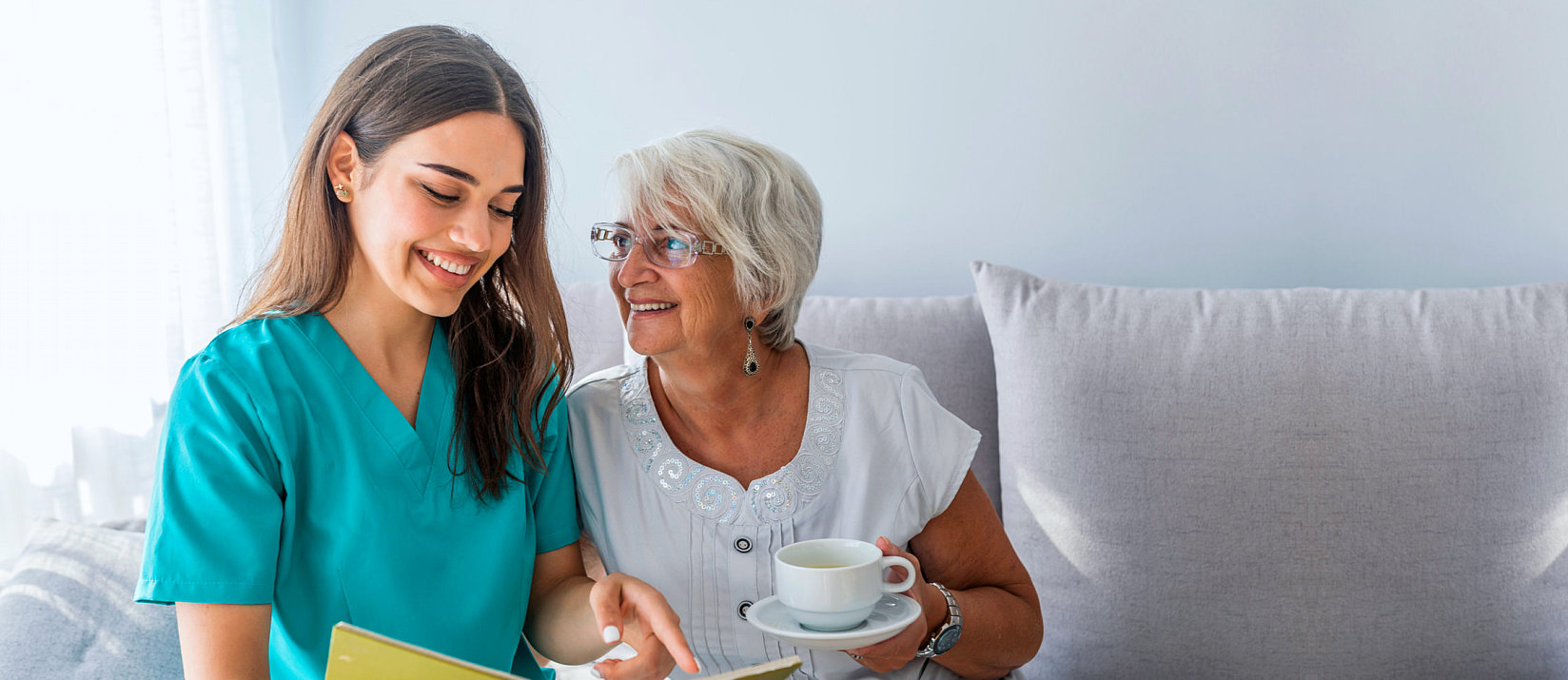 Healthcare worker with elderly woman on couch clipboard